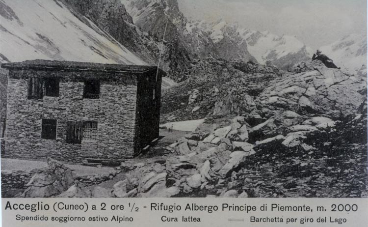 Silvio Turra, il proprietario del Rifugio, ha voluto dare un tocco di originalità alla fotografia, mettendosi in posa vicino alla casa, sulla roccia a destra.