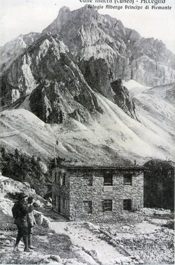 Altra immagine del Rifugio-Albergo: due persone stanno osservando il lago Visaisa; sullo sfondo, il monte dell'Auto Vallonasso.